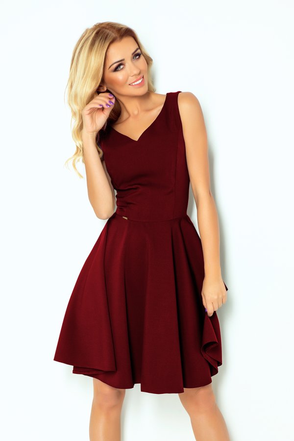 A woman is wearing a sleeveless, burgundy dress with a fitted bodice and a flared skirt. The dress features a subtle V-neckline, creating an elegant and timeless look.