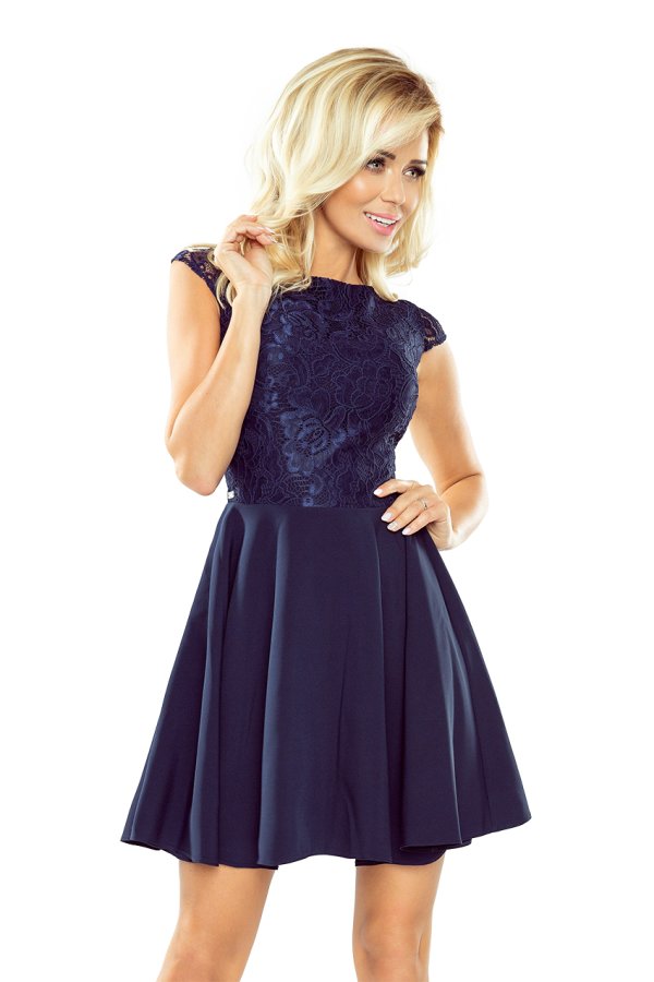 A woman is wearing a navy blue dress featuring a lace bodice and a flared skirt. The dress has cap sleeves and offers an elegant, classic look.