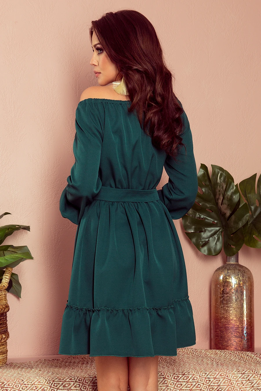 The image features an elegant off-the-shoulder dress in a rich emerald green color, with a cinched waist and ruffled hemline. The dress exudes a sophisticated and stylish look, perfect for both casual and formal occasions.