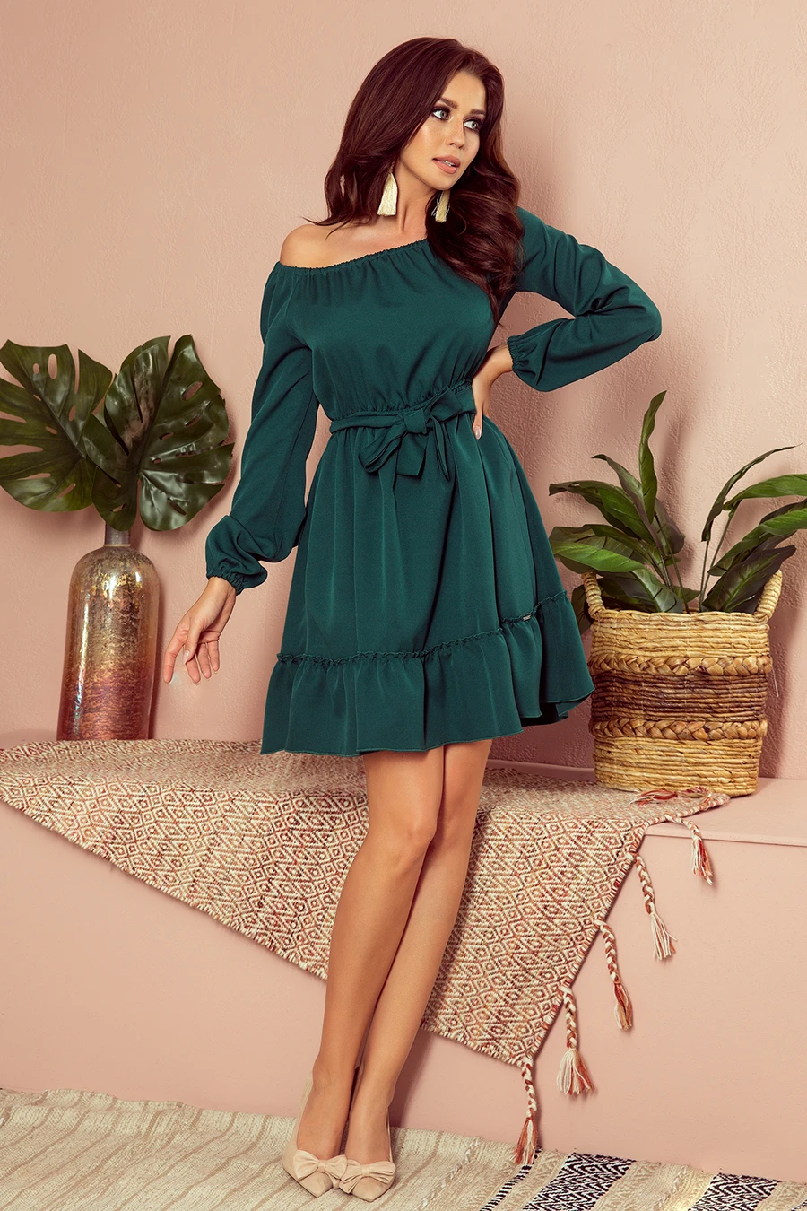 A stylish off-the-shoulder green dress with long sleeves and a cinched waist, perfect for a chic and elegant look. The dress features a ruffled hem and a matching belt, adding a touch of sophistication.