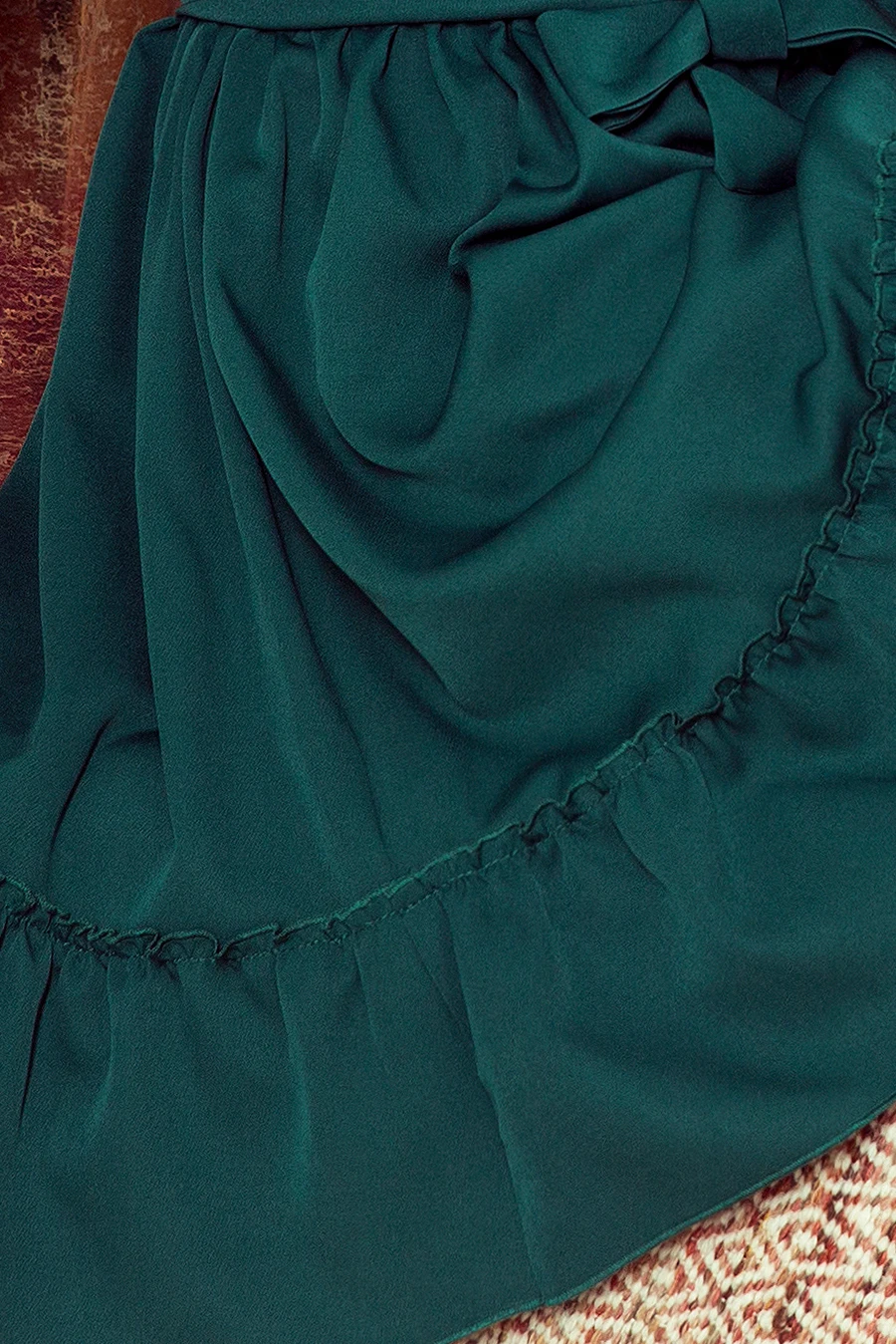 A flowing green skirt with delicate ruffles and a bow detail adds elegance to any outfit. The fabric drapes beautifully, creating a sophisticated and stylish look.