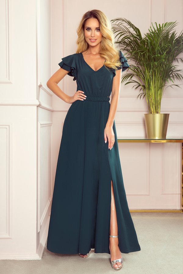 A long, elegant dark green dress features ruffled sleeves and a stylish side slit. The dress is paired with silver high-heeled sandals, creating a sophisticated look.