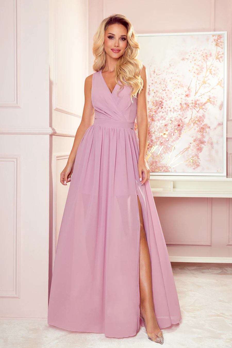 A long, elegant pink dress with a deep V-neckline and a high slit, perfect for formal occasions. The dress features a fitted waist and flowing skirt, adding a touch of sophistication and grace.