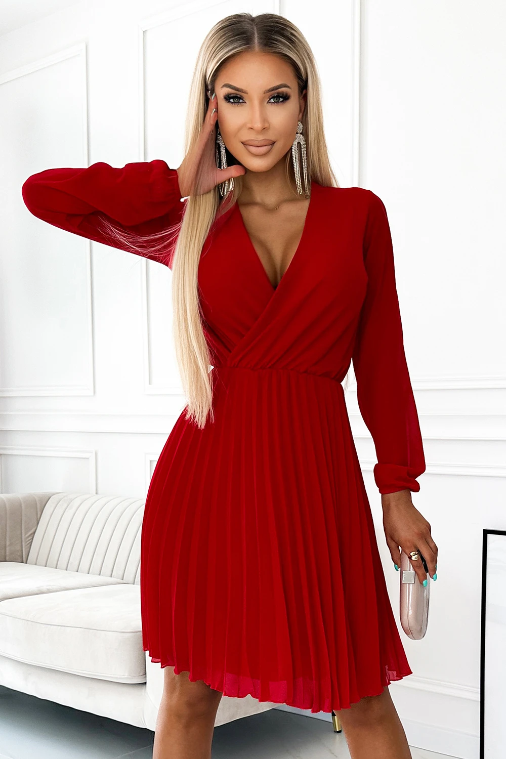 A stylish red dress with long sleeves and a pleated skirt, perfect for elegant occasions. The deep V-neckline adds a touch of sophistication to the overall design.