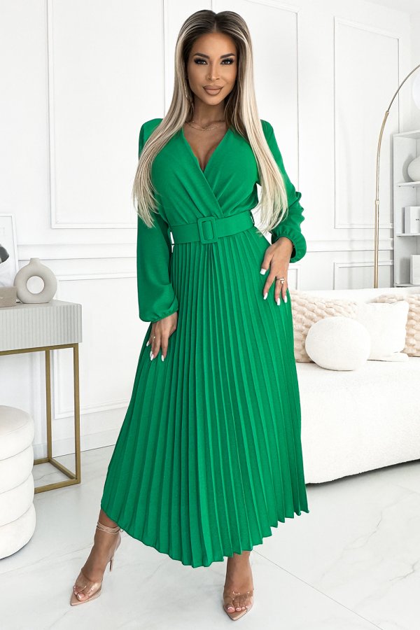 A vibrant green dress with a pleated skirt and a matching belt creates an elegant silhouette. The long sleeves and deep V-neckline add a sophisticated touch to the design.