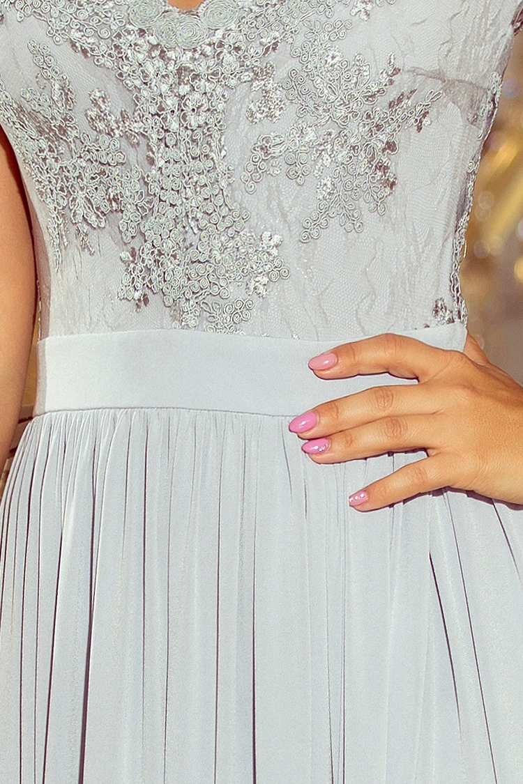 A delicate light gray dress features intricate lace detailing on the bodice, complemented by a flowing pleated skirt. The elegant design is perfect for formal occasions, offering a sophisticated and timeless look.