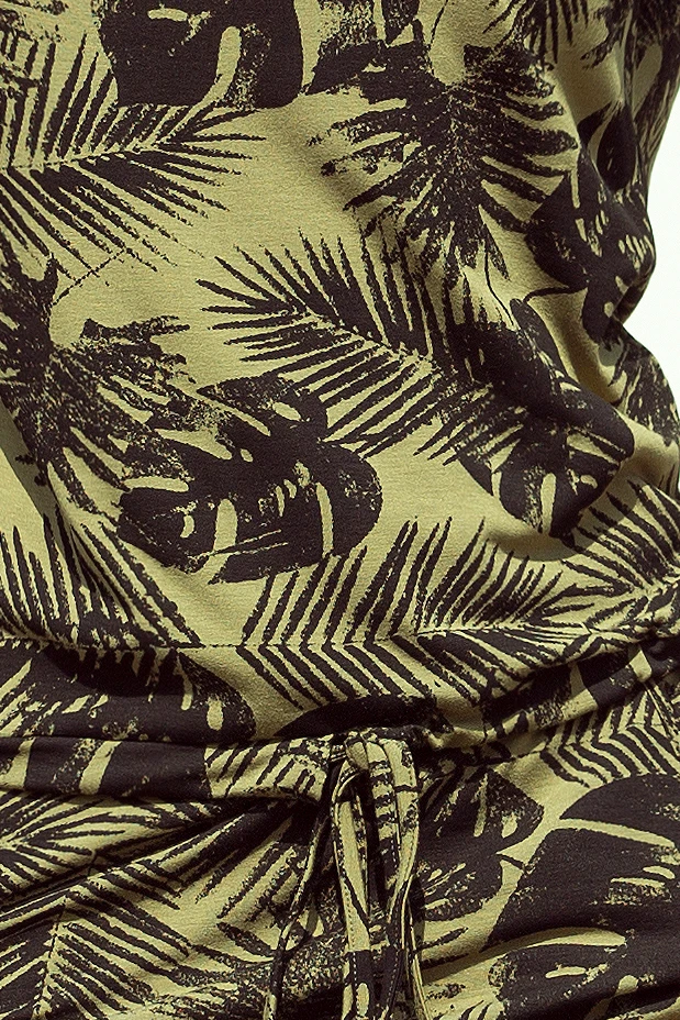 A close-up of a garment featuring a tropical leaf pattern in dark tones on a light olive background. The fabric is gathered with a drawstring, adding a casual and adjustable fit.