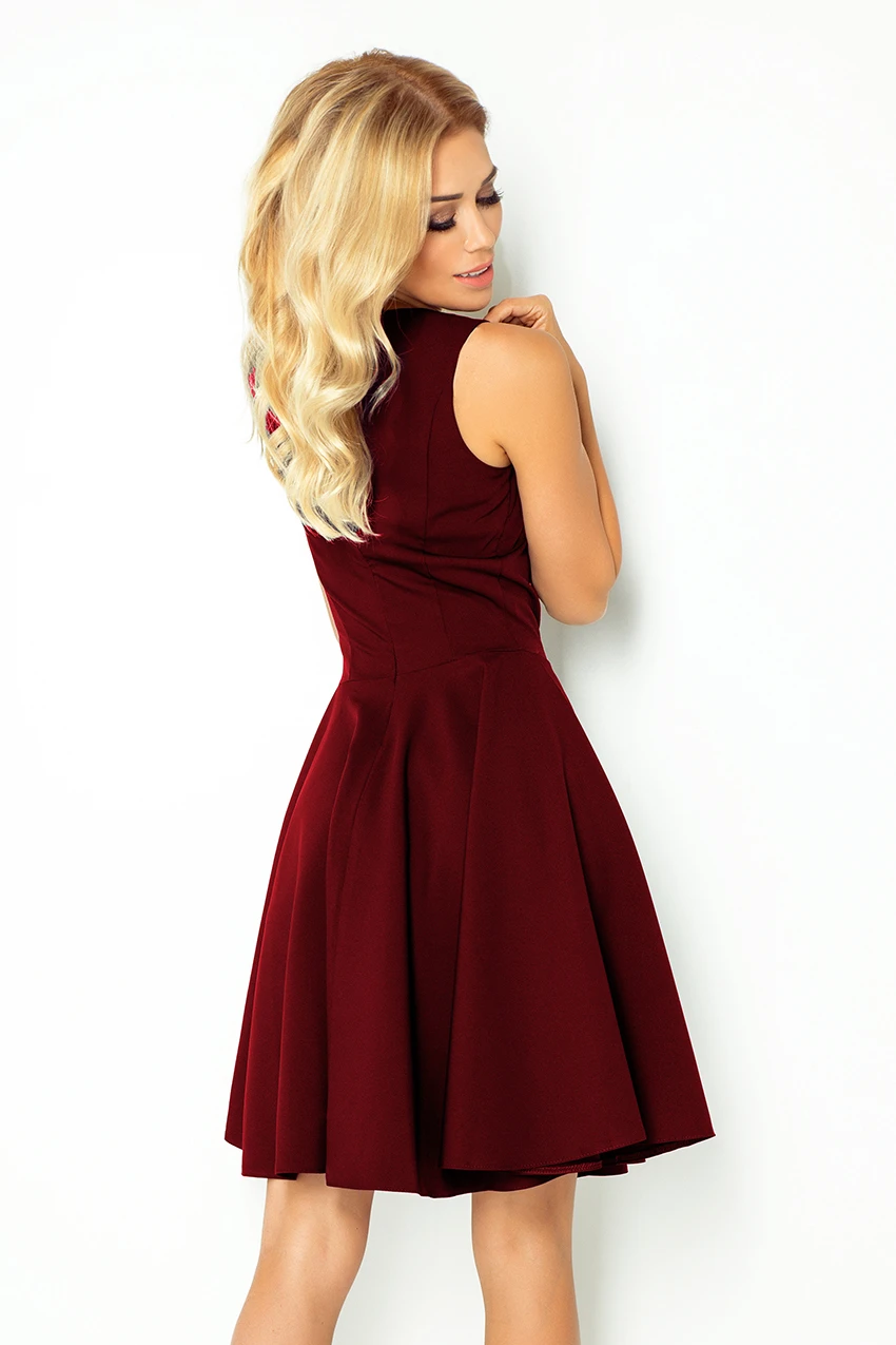 A woman is wearing a sleeveless, burgundy dress with a flared skirt. The dress features a fitted bodice and a classic, elegant design.