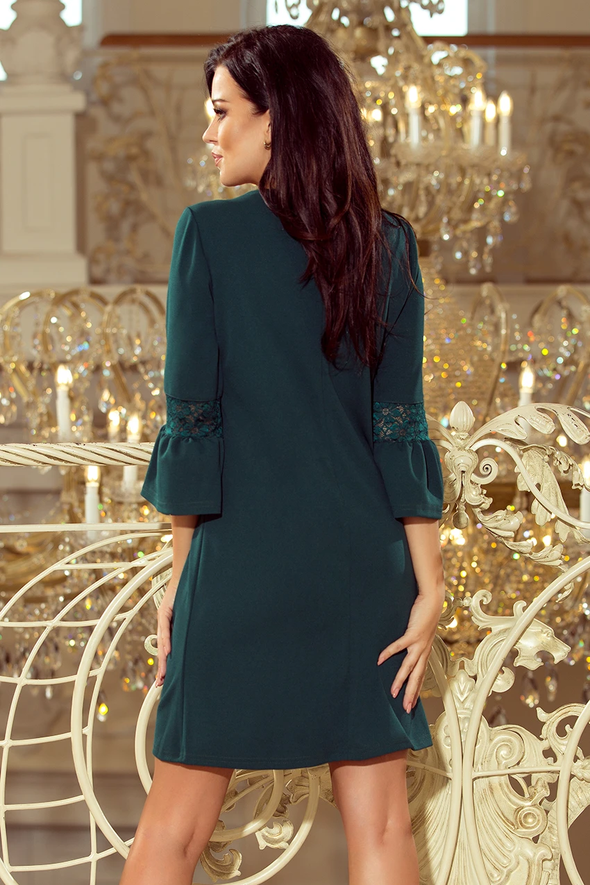 A woman is wearing an elegant dark green dress with lace details on the sleeves. The dress features a simple yet sophisticated design, perfect for formal occasions.
