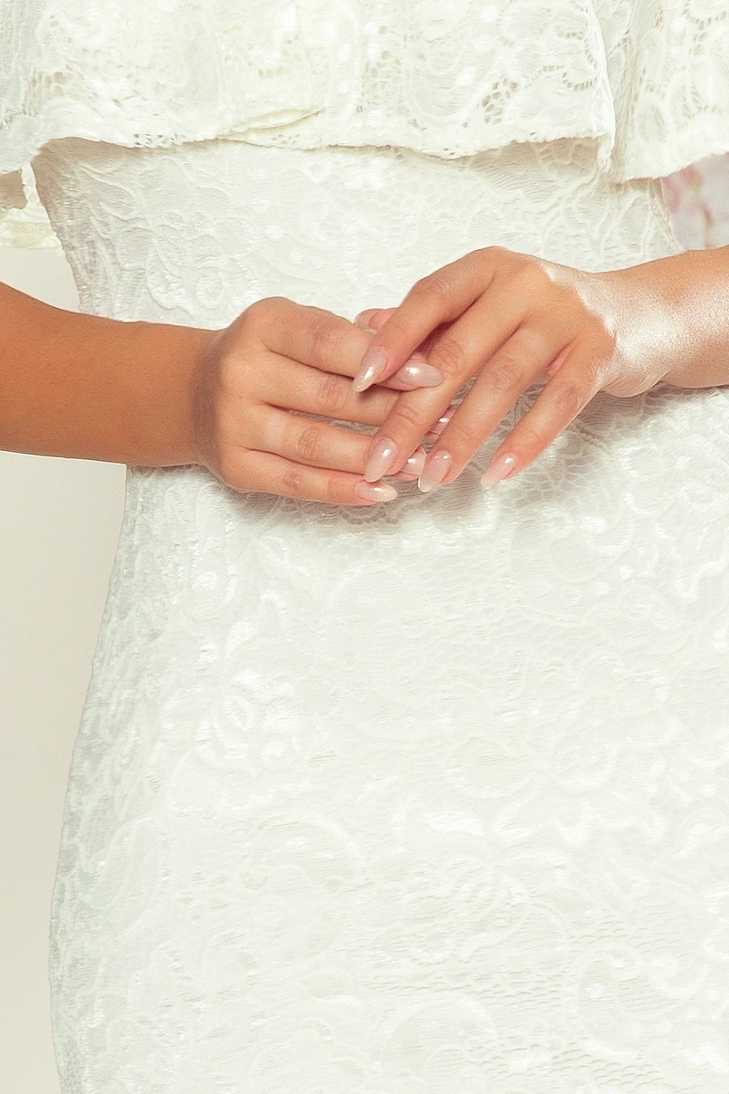 The image showcases a close-up of a white lace dress with intricate floral patterns. The fabric appears delicate and elegant, perfect for formal occasions.