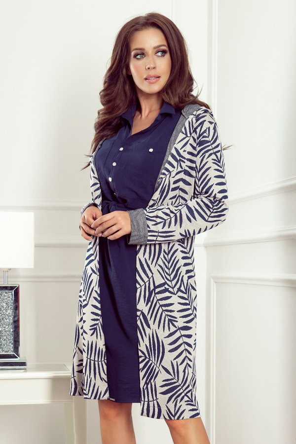 A stylish woman is wearing a navy blue dress paired with a long, patterned cardigan featuring a leaf design. The outfit exudes elegance and comfort, perfect for both casual and formal settings.