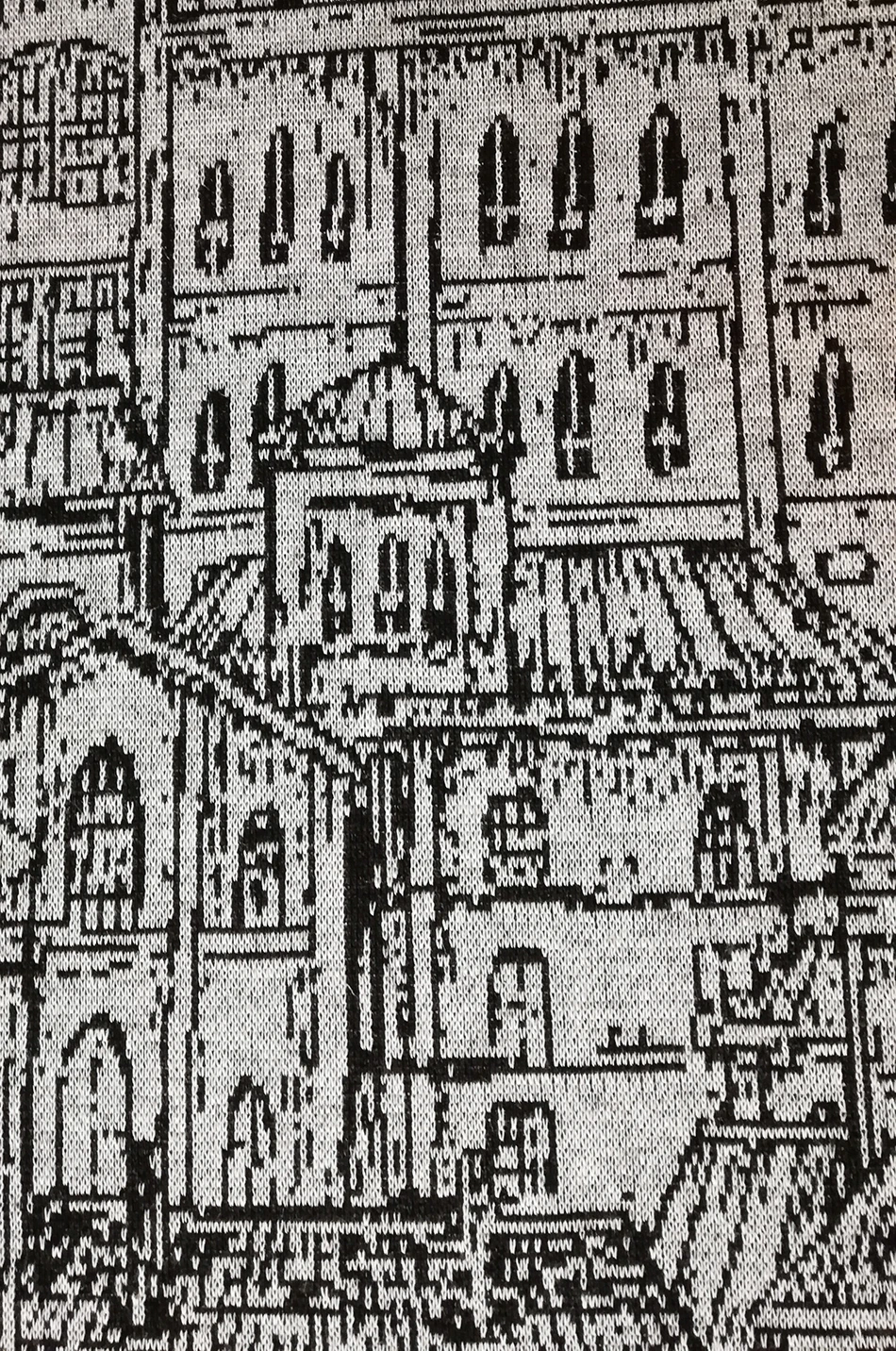 The image shows a detailed black and white knitted fabric featuring an intricate architectural pattern. The design includes various windows and structures, creating a classic and elegant look.