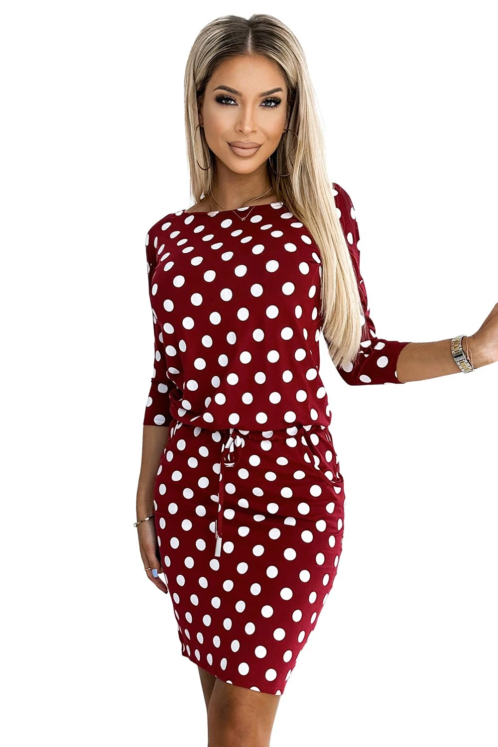 The woman in the photo is wearing a stylish beige dress with a belted waist, highlighting the elegant design of the dress. The model showcases the dress\'s sophisticated cut and soft fabric, perfect for any formal occasion.