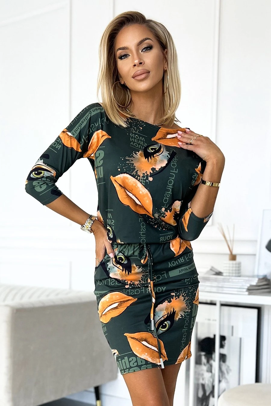 The woman in the photo is wearing a stylish printed dress featuring bold, artistic designs. This eye-catching dress showcases a unique blend of colors and patterns, perfect for making a fashion statement.