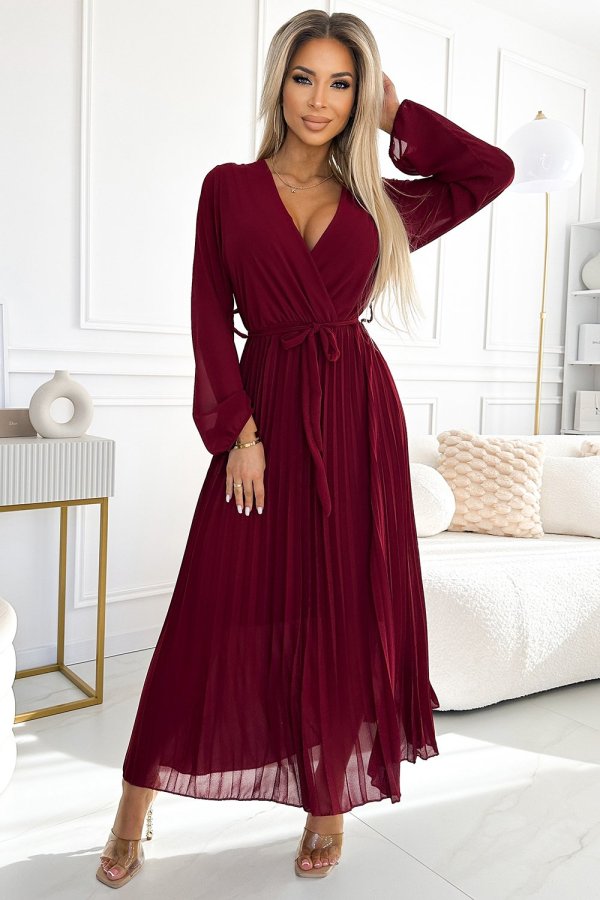 The woman in the photo is wearing a stunning burgundy pleated maxi dress, showcasing its elegant flow and rich color. This maxi dress adds a touch of sophistication to any setting, perfect for both casual and formal occasions.