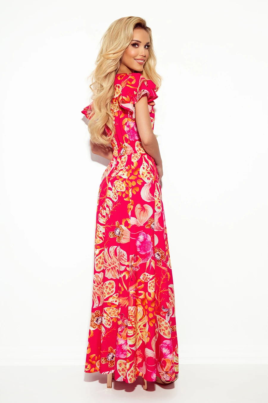 A vibrant, floor-length dress features a bold floral pattern in shades of pink, orange, and yellow. The design includes ruffled sleeves, adding a touch of elegance and femininity.