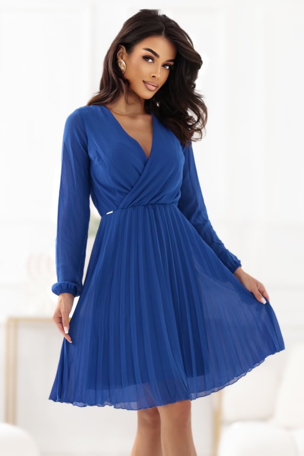 The woman in the photo is wearing a stunning blue pleated dress, perfect for elegant occasions. This chic blue dress features long sleeves and a flattering fit, making it a must-have addition to any wardrobe.