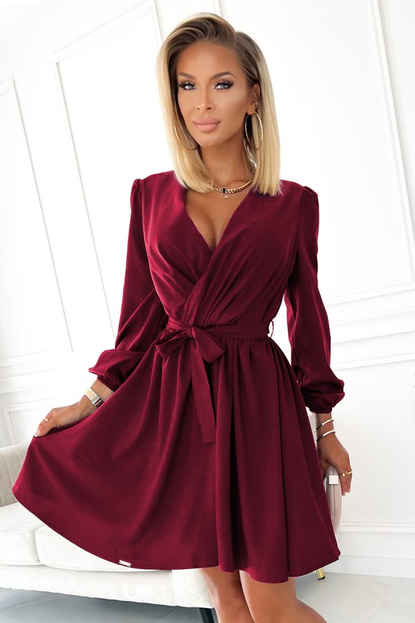 A stylish burgundy dress with a flattering wrap design and a waist tie accentuates elegance and sophistication. The long sleeves and flowing skirt make it perfect for both formal and casual occasions.