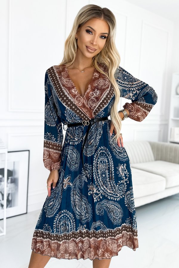 A woman is wearing a stylish, long-sleeved dress with a blue and brown paisley pattern, cinched at the waist with a black belt. The dress features intricate detailing and a flowing skirt, perfect for a chic and elegant look.