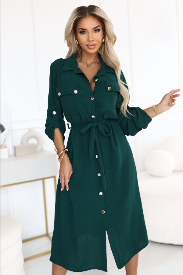 The image showcases a stylish, knee-length green shirt dress featuring button-up details and a waist tie, perfect for versatile wear. This elegant shirt dress is designed with long sleeves that can be rolled up, adding a chic touch to your wardrobe.