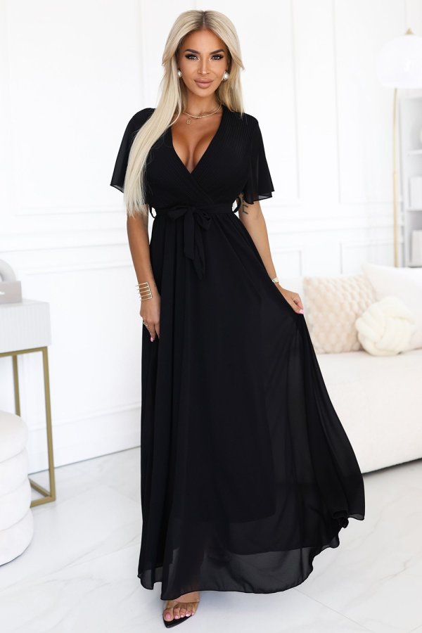 The woman in the photo is wearing an elegant black maxi dress, showcasing its flowing silhouette and sophisticated design. This black dress is perfect for formal occasions, highlighting its timeless appeal and graceful style.