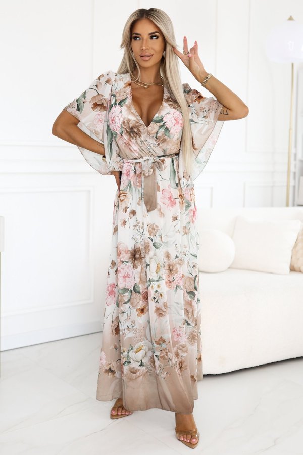 The woman in the photo is wearing a flowing floral maxi dress, showcasing its elegant design and pastel colors. This floral maxi dress perfectly complements a sophisticated and stylish look for any occasion.