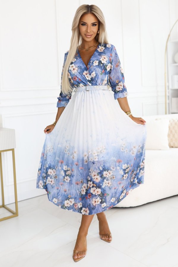 The woman in the photo is wearing a stunning floral dress with a flowing, pleated design, perfect for spring occasions. This elegant floral dress features vibrant blue and white hues, adding a touch of sophistication to any wardrobe.